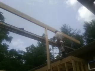 Carpenter setting a ridge beam over a new addition frame — Ice Dam Removal by Roofing Brothers in Paulina