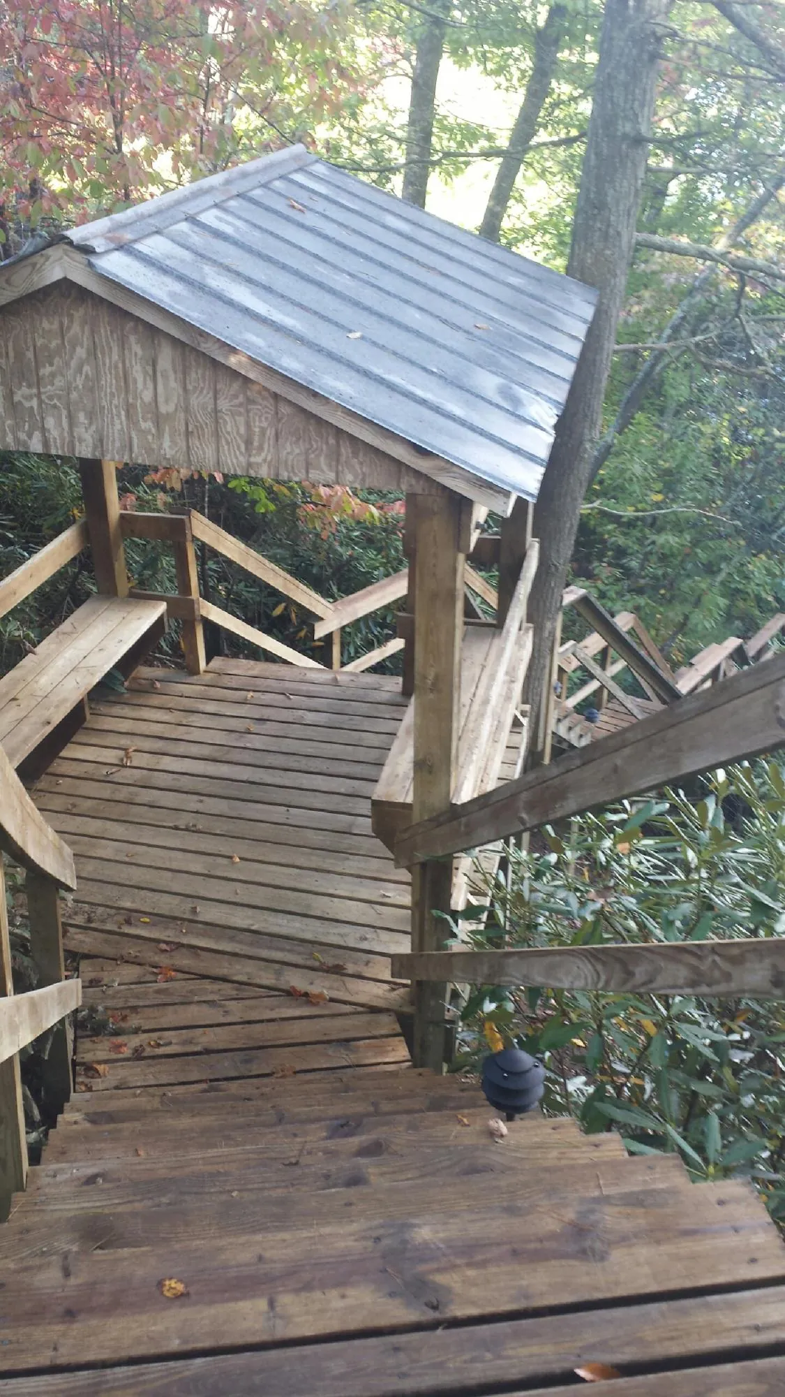 Metal roofed shelter over wooden steps on a wooded walkway — Skylight Repair & Installation work by our crew in Paulina