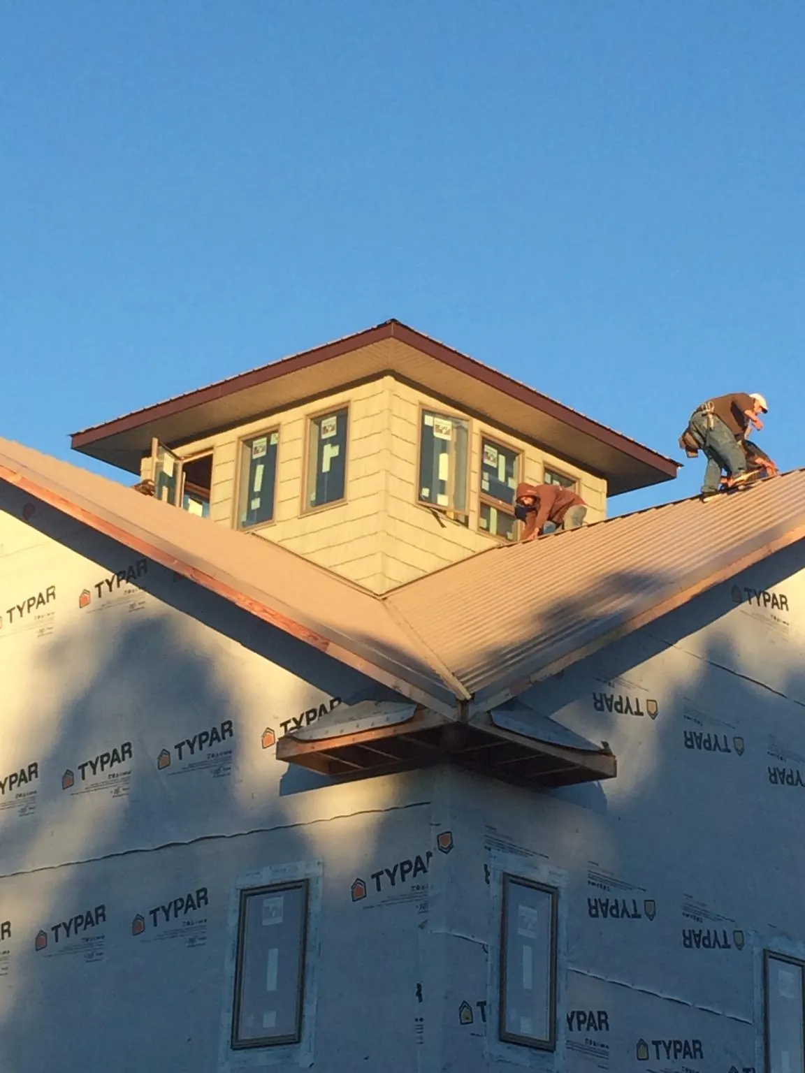 Roofers working around a rooftop cupola on a new metal roof at sunset — Roof Waterproofing in Paulina by Roofing Brothers